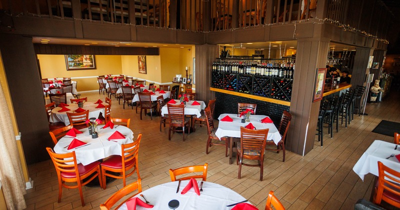 Interior, tables and chairs near the wall filled with wine bottles