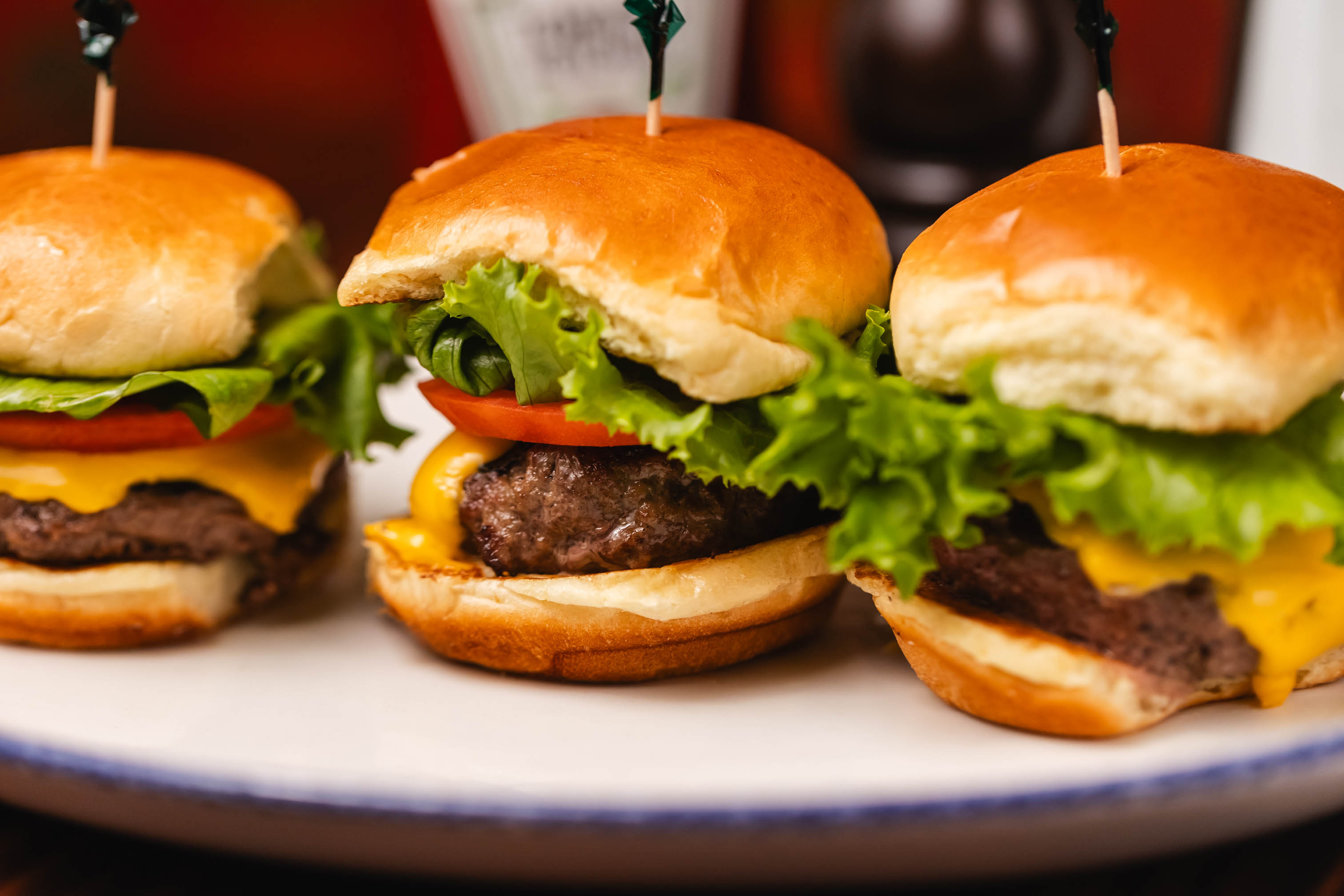 Three cheeseburger sliders served on a plate, close-up