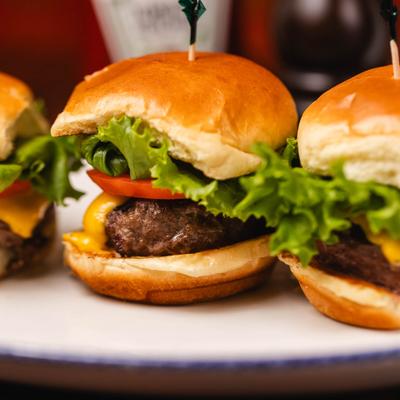 Three cheeseburger sliders served on a plate, close-up.