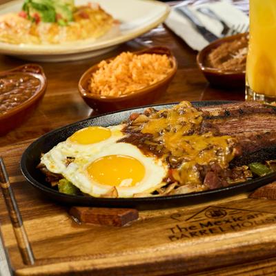 Breakfast Fajita with brisket, vegetables and fried eggs, served with sides.