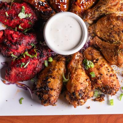 Platter of chicken wings featuring different seasoning styles with a dip.