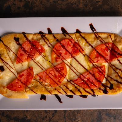 Caprese Flatbread, with garlic butter, mozzarella, tomato, Romano cheese, and balsamic.