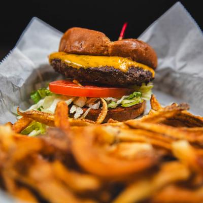 Burger is served with a side of fries on parchment paper, close-up.