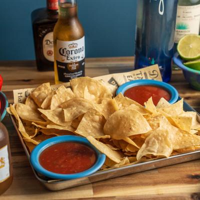 Tray of tortilla chips served with two small bowls of red salsa.
