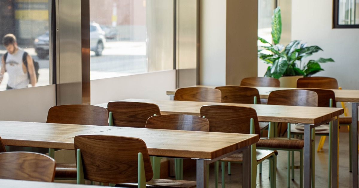 Modern interior with wooden tables and chairs, large windows