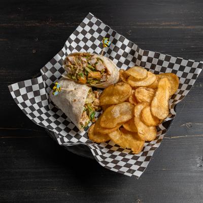 Chicken Caesar Wrap sliced in half and served with a side of chips.