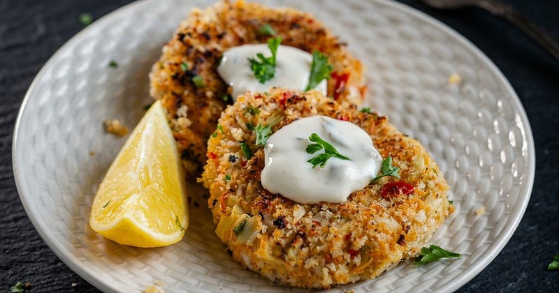 Vegan crab cakes served with sauce and lemon wedge