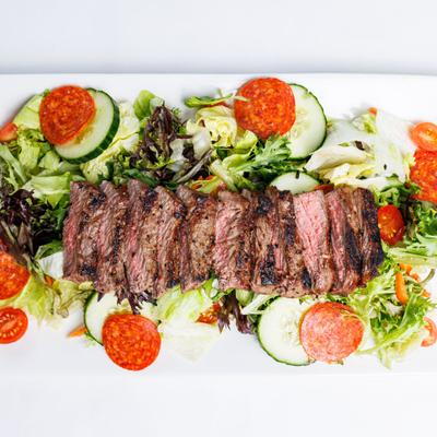 Salad with mixed vegetables and grilled steak.