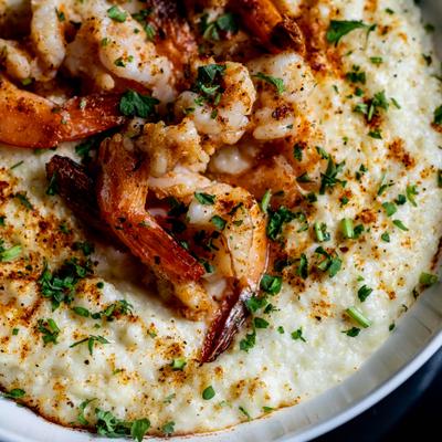 Shrimp and grits garnished with chopped herbs, close-up.