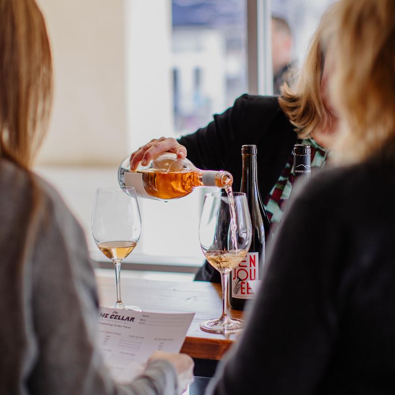 Person pouring rose wine for the customers.