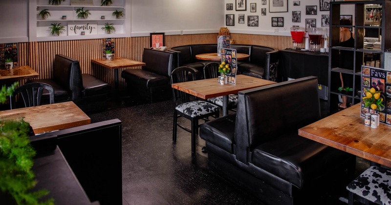 Dining area with wooden tables, black cushioned seating, decorated walls, and beverage dispensers