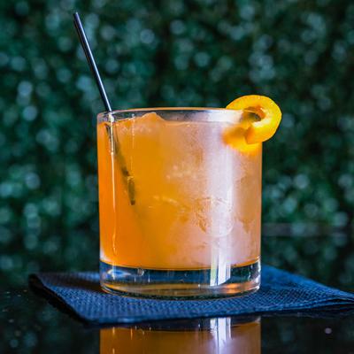 Orange Cocktail garnished with lemon peel.