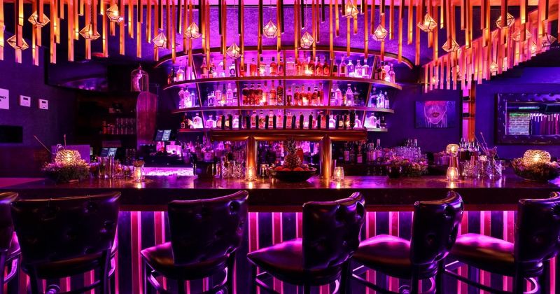 A bar with chairs and drinks rack behind