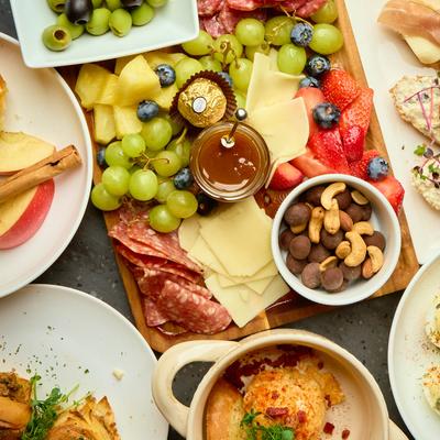 Assortment of dishes with charcuterie board as the centerpiece, top view.
