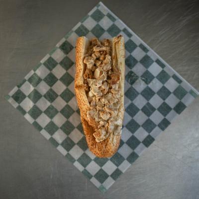 Chicken cheesesteak sandwich served on checkered paper.