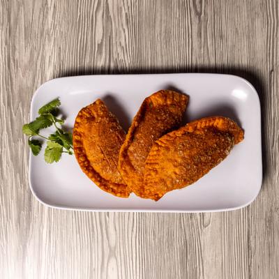 Three empanadas on plate, top view.
