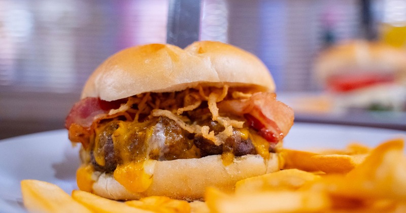 A bacon cheeseburger with a side of french fries
