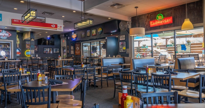 Interior with wooden tables, black chairs and neon signs on dark walls