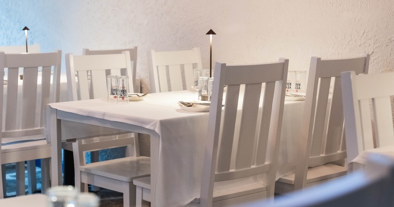 Interior, dining area, closeup on a single set up table with white wooden chairs