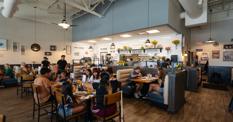 Interior,  diner area full of people, tables and chairs, bar, stools