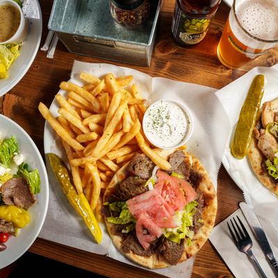 Gyros Souvlaki, topped with onion, tomato, lettuce, and served with fries and tzatziki.