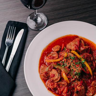 Sausage & Peppers with marinara and white wine, served with a glass of red wine.