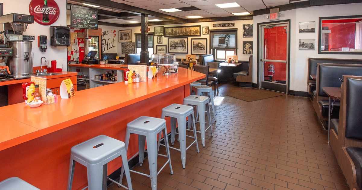 Interior of a diner featuring an orange countertop, metal bar stools, and booths