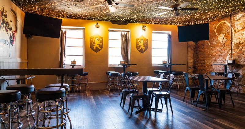 Seating area with tables and chairs, and barstools. Two big TVs in the corners