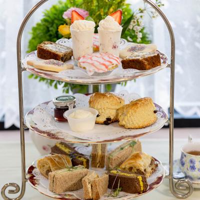 Various scones, tea sandwiches, and desserts on a tiered stand.