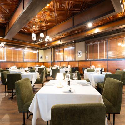 Elegant restaurant interior with green chairs and tables covered in white linens.