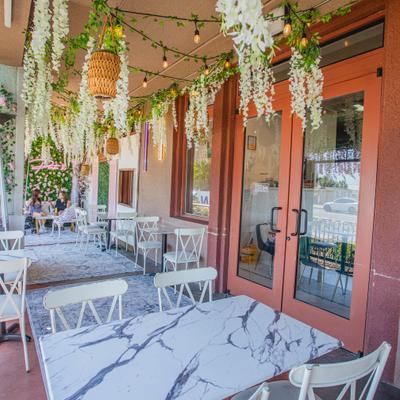 Outdoor patio dining area with marble tables, string lights, and floral decorations.