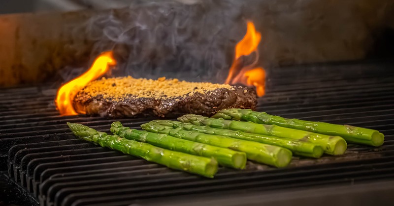 Meat and asparagus cooking on grill