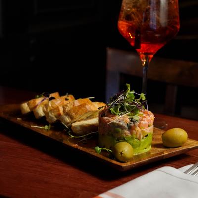 Salmon Tartare served with toast, alongside a cocktail.