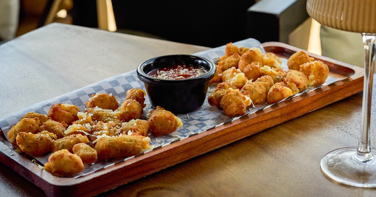 Cheese curds served on a wooden tray with a dipping sauce