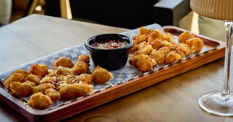 Cheese curds served on a wooden tray with a dipping sauce