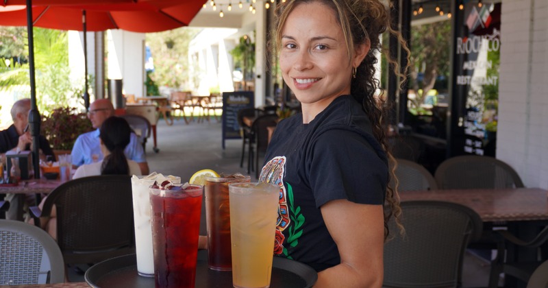 A bartender pouring drink into a cocktail jigger