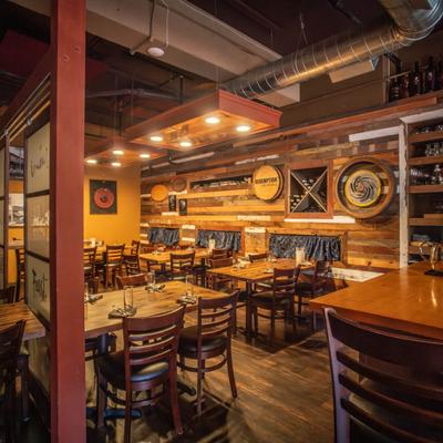 Rustic restaurant dining area with wooden tables, chairs, and a reclaimed wood accent wall.