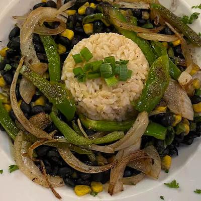 A dish with black beans, onions, grilled rice, and corn.