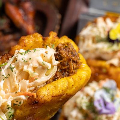 Close-up of a plantain taco with slow-cooked pork rib and coleslaw.