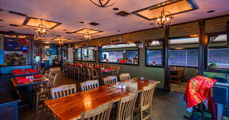 Warmly lit restaurant interior with wooden tables, chairs, globe chandeliers