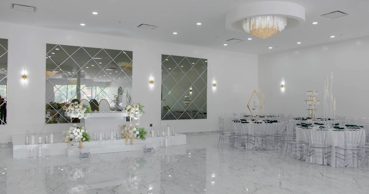 Spacious event hall, white marble floors, mirrored walls, floral arrangements and elegant decor