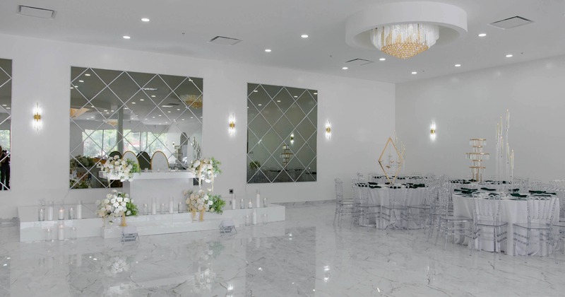 Spacious event hall, white marble floors, mirrored walls, floral arrangements and elegant decor