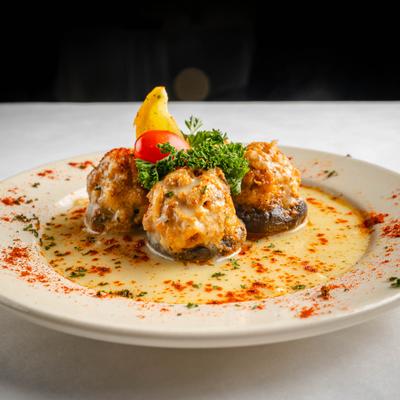 Stuffed Mushrooms garnished with cherry tomato, fresh herbs and lemon slice.