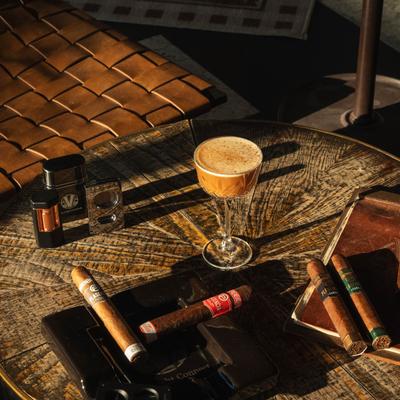 Johnny Appleseed cocktail placed on a table with cigars