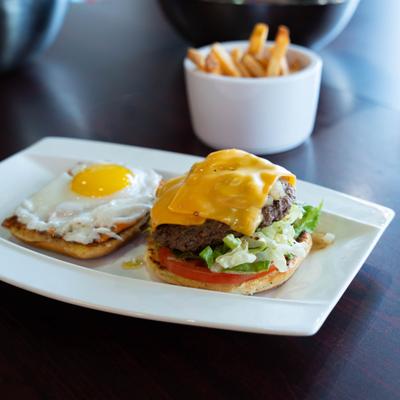 Cheeseburger with a fried egg, mushrooms, onion strings, pickles, tomato, and lettuce.
