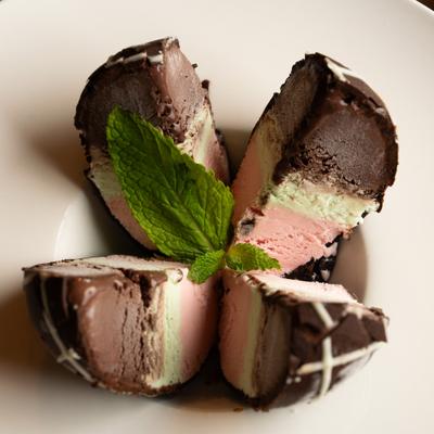 Spumoni molded gelato consisting of three distinct layers and mint garnish.