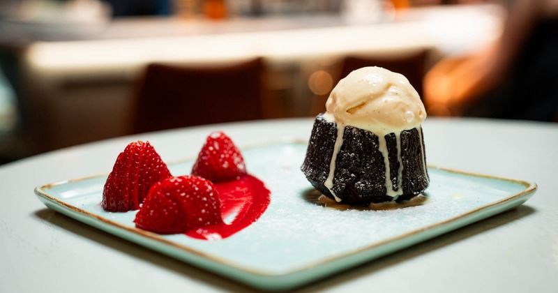 Lava cake served on a square plate garnished with strawberry sauce