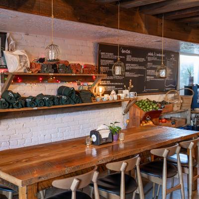 Interior with a chalkboard menu, wooden tables, pendant lights, and fresh produce.