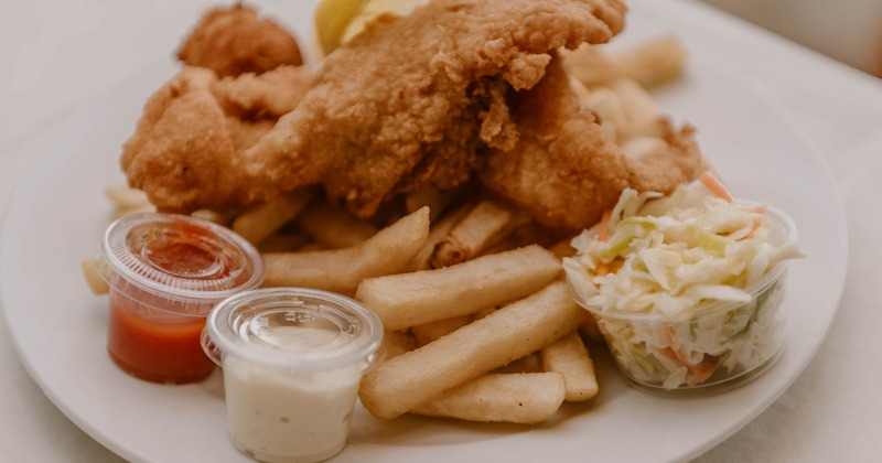 Fried fish served with fries, coleslaw and dipping sauces