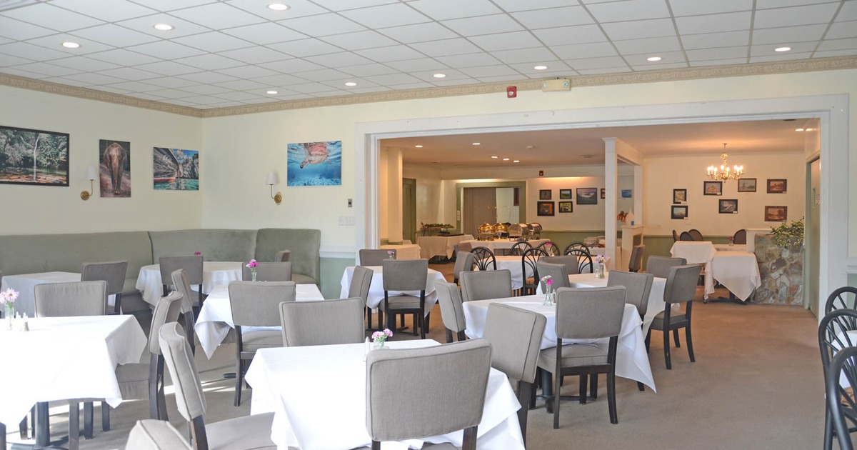 Interior with wood floors, tables, chairs, large windows, and decorative lighting